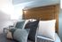 Inviting bedroom with a wooden headboard, plush pillows, and cozy textiles.