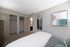 Elegant bedroom with modern decor, featuring a large closet, wall mirror, and abstract art piece.