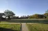 Serene view of lush green lawn and picturesque trees under a clear blue sky, perfect for relaxation and outdoor activities.