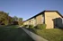 Inviting brick apartment building with lush green surroundings and a charming walkway under a clear blue sky.