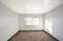 Bright and inviting empty room with soft carpeting and large window, perfect for personalization.
