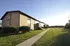 Charming brick apartment complex with sunlit exterior, surrounded by lush greenery and spacious lawn.