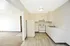 Charming apartment kitchen with sleek white cabinetry, modern appliances, and a cozy adjacent carpeted living area.