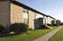 Charming brick apartment building with well-maintained landscaping and inviting entrances, basking in warm sunlight.