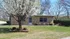 Charming brick home with a blooming tree in front, surrounded by vibrant flower decorations and lush greenery, offering a serene and inviting atmosphere.