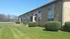 Charming brick apartment building with well-maintained landscaping and lush green lawn under a clear blue sky.