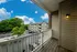 Charming apartment balcony view overlooking serene green landscapes and a spacious parking lot with clear blue skies.