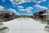 Inviting outdoor pool area with modern sun loungers, shade umbrellas, and vibrant blue skies, surrounded by charming brick apartment buildings.