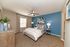 Elegant bedroom with modern design, featuring a cozy bed, vibrant blue accent wall, and stylish decor.