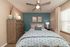 Inviting bedroom with elegant decor, featuring a cozy bed with patterned pillows, a stylish dresser, and serene lighting creating a relaxing ambiance.