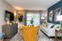 Contemporary living room featuring a vibrant mustard chair, cozy gray sofa, modern decor, and natural light streaming through elegant drapes.