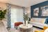 Bright, modern living room with elegant blue accent wall, cozy grey sofa, vibrant cushions, and stylish curtains framing a garden view.