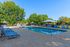 Inviting outdoor pool area with sun loungers and shaded seating, surrounded by lush greenery, perfect for relaxation and leisure.