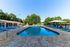 Inviting outdoor pool area with sleek lounge chairs, surrounded by lush greenery and shaded pavilions.