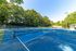 Vibrant outdoor tennis court surrounded by lush greenery, perfect for sports enthusiasts.