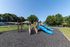 Inviting playground with vibrant blue slides and a sturdy climbing structure, surrounded by scenic greenery, perfect for family enjoyment.