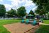 Charming outdoor space with vibrant turquoise chairs, a stylish BBQ grill, and lush greenery, perfect for relaxing and entertaining.
