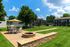 Charming apartment complex with inviting outdoor patio, lush green lawns, and a cozy fire pit under a sunny sky.