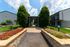 Charming apartment entrance with a lush landscaped path, vibrant flower beds, and modern architecture.