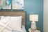 Tranquil bedroom corner with a cozy wooden headboard, abstract art, and a stylish lamp on a side table.