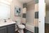 Modern bathroom with chic blue and beige curtains, stylish vanity, and contemporary artwork.