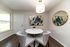 Chic dining area with a modern round table and stylish chairs, complemented by elegant abstract art and natural light.