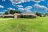 Charming single-story brick home with a well-manicured lawn under a beautiful blue sky.