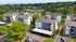 Aerial view of charming apartment complex surrounded by lush greenery and modern amenities, featuring spacious balconies and ample parking in a serene neighborhood setting.