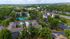 Vibrant aerial view of a modern apartment community with lush greenery, tennis courts, and ample parking nestled in a serene neighborhood.