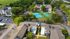 Bird's eye view of a modern apartment complex featuring lush greenery, tennis courts, and ample parking, offering a vibrant community lifestyle.