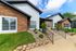 Charming exterior of a modern apartment complex with stone accents, lush landscaping, and inviting walkway.