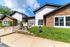 Charming leasing center with a modern stone exterior, surrounded by manicured landscaping and bright blue skies.