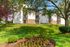 Charming apartment complex with elegant balconies surrounded by lush greenery and vibrant flower beds.