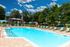Inviting outdoor pool area with vibrant sun loungers, shaded seating, and lush greenery, perfect for relaxation and leisure under a sunny sky.