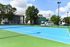 Vibrant apartment complex with spacious tennis courts surrounded by lush greenery, perfect for active living.