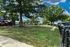 Charming outdoor space with lush green lawn, mature trees, and a fenced pathway, perfect for relaxing and enjoying nature.