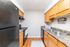 Cozy kitchen with modern black appliances, warm wooden cabinetry, and stylish granite countertops, offering a welcoming and functional space.