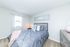 Inviting bedroom with plush gray bedding, modern decor, and natural light streaming through a window.