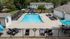 Inviting outdoor pool area with modern lounge chairs, surrounded by lush greenery and a play area, perfect for relaxation and family fun.