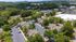 Scenic aerial view of a charming apartment complex surrounded by lush greenery and ample parking, offering a peaceful residential environment.