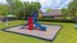 Inviting community playground featuring a vibrant red and blue slide set amid lush green surroundings, perfect for family enjoyment.