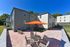 Charming apartment exterior with a spacious patio, featuring stylish outdoor seating and a vibrant orange umbrella set against a clear blue sky.