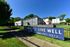 Inviting apartment complex with spacious green lawns and modern architecture, promoting prime living with the motto 'Live Here, Live Well'.