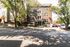 Charming brick apartment building surrounded by lush trees, offering a welcoming entrance and convenient parking.