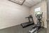 Chic apartment fitness room with a treadmill and elliptical, featuring exposed brick and cozy natural light.