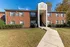 Charming brick apartment complex with classic architecture and manicured landscaping, featuring a welcoming entrance under a bright blue sky.