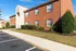 Inviting brick apartment building with classic architecture, surrounded by lush greenery and ample parking spaces.