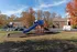 Inviting residential outdoor scene featuring a vibrant playground with a blue slide, surrounded by lush autumn trees and a welcoming apartment complex in the background.