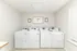 Bright and clean laundry room featuring four modern washing machines, enhanced by natural light from large windows.