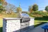 Stylish outdoor barbecue area with a sleek stainless steel grill set on a charming stone base, perfect for entertaining amidst a serene green landscape.